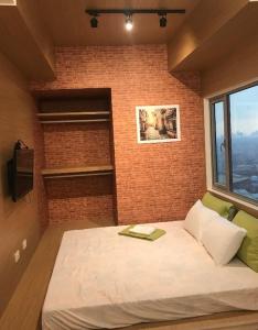 a bed in a room with a brick wall at The grass residences sm north edsa cozy comfortable heart of Quezon City in Manila