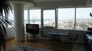 a room with a desk and a computer in a room with windows at 25-th Floor Sea View Apartment in Klaipėda