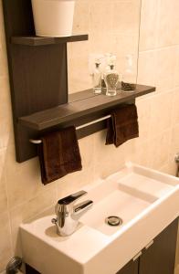 a bathroom with a white sink and a shelf at B&B Rosaverde in Mulazzano