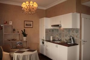 una cucina con armadi bianchi, tavolo e lampadario pendente di Les 4 Tilleuls a Crozant
