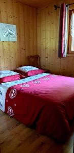 Bett in einem Zimmer mit einer roten Decke in der Unterkunft Entre Giffre et Valentine in Verchaix
