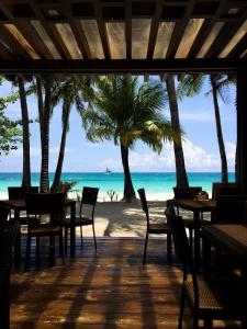 un restaurante en la playa con palmeras y el océano en 357 Boracay Resort, en Boracay
