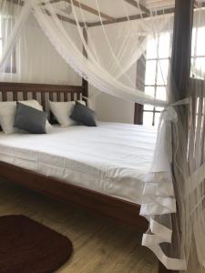 une chambre avec un lit avec moustiquaire dans l'établissement The Dalawella Porch House, à Galle