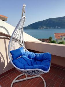 una silla colgante con almohadas azules en el balcón en Villa Nena en Herceg-Novi