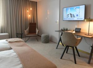 a hotel room with a bed and a desk and a tv at Kongress Hotel Davos in Davos