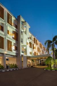 a large white building with palm trees in front of it at Swiss-Belinn Cibitung in Cibitung