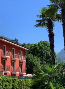 a red building with a palm tree in front of it at B & B Sul Lago in Porlezza