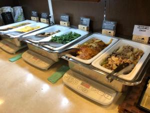 un buffet con diferentes tipos de comida en bandejas en Super Hotel JR Ikebukuro Nishiguchi, en Tokio