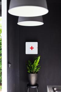 a red cross sign on a black wall with a plant at The Seaton House in Rawai Beach