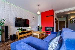 sala de estar con sofá azul y TV en Lawendowy Zakatek en Stegna