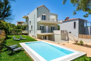 a villa with a swimming pool in front of a house at SP villa in Agios Onoufrios