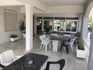 a patio with white chairs and a table on a porch at Dionisos Blue in Paralia Dionysiou