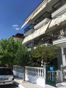 a building with balconies and a car parked in front at Dionisos Blue in Paralia Dionysiou