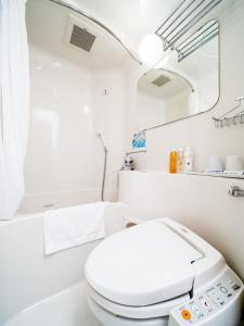 a white bathroom with a toilet and a mirror at Super Hotel Natural Hot Springs Fuji Honkan in Fuji