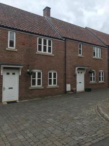 a brick building with two white doors and windows at 3 Crown Barton, Glastonbury in Glastonbury