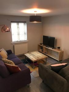 a living room with a couch and a table and a tv at 3 Crown Barton, Glastonbury in Glastonbury