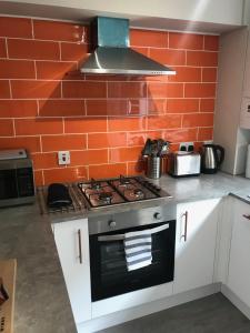 a kitchen with a stove and an orange brick wall at 3 Crown Barton, Glastonbury in Glastonbury
