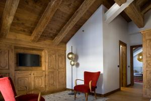 una sala de estar con techos de madera y sillas rojas. en Hotel Cortina, en Cortina dʼAmpezzo