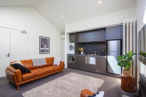 a living room with a brown couch and a kitchen at The Arrow Nest in Arrowtown