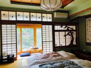 een slaapkamer met een bed in een kamer met ramen bij Otarunishikien in Otaru