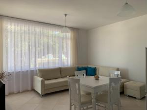 a living room with a couch and a table and chairs at EME APARTMENTS - Kompleksi Lura 2 Gjiri i Lalzit in Draç