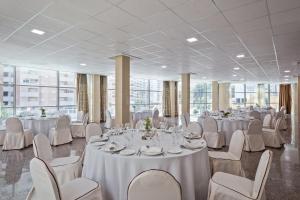 a banquet hall with white tables and chairs at Cullera Holiday in Cullera