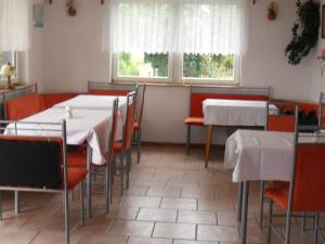 comedor con mesas y sillas y 2 ventanas en Pension Sabine, en Ummanz