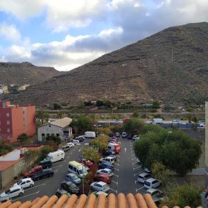 a parking lot with cars parked in front of a mountain at apartamentos la villa 3 in San Sebastián de la Gomera