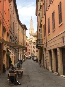 eine Straße mit Gebäuden und Menschen, die an Tischen sitzen in der Unterkunft Modena Charme Sant'Eufemia in Modena