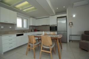 - une cuisine avec des placards blancs, une table et des chaises dans l'établissement Villa Maria, à Makry Gialos