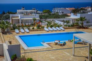 una piscina con sillas y una villa en el fondo en Villa Maria, en Makrí Gialós