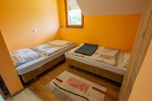 two beds in a room with orange walls at Bled Honey Bee Apartment in Bled