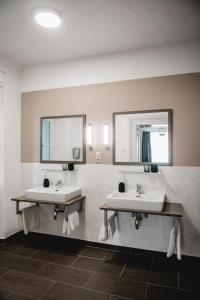 ein Badezimmer mit zwei Waschbecken und zwei Spiegeln in der Unterkunft Das Gästehaus in Sankt Veit am Vogau