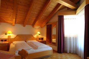 um quarto com uma cama e uma grande janela em Pensione Edelweiss em San Cassiano