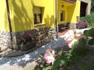 a yellow house with flowers and a stone wall at APARTAMENTOS RURALES PERNÚS in Colunga +1 photo