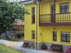 a yellow building with a balcony and a bench at APARTAMENTOS RURALES PERNÚS in Colunga