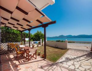 patio ze stołem i krzesłami pod pergolą w obiekcie Irini seaside studios w mieście Nikiana
