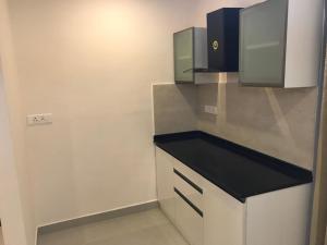 a kitchen with white cabinets and a black counter top at Apollostay in Chennai