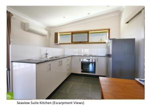 uma cozinha com armários brancos e um frigorífico de aço inoxidável em Southview Guest House em Wollongong