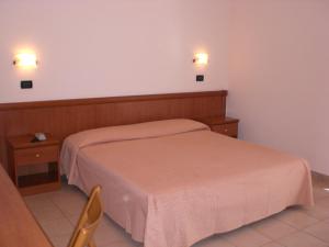 a bedroom with a bed and two lights on the wall at Hotel Sirios in San Giovanni Rotondo