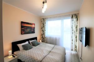 sypialnia z łóżkiem i dużym oknem w obiekcie Apartament Superior Pastelowy Przy Plaży w Kołobrzegu