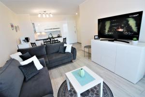salon z kanapą i telewizorem z płaskim ekranem w obiekcie Apartament Superior Pastelowy Przy Plaży w Kołobrzegu