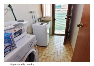 a laundry room with a washing machine and a refrigerator at Hopetoun Villa in Woonona