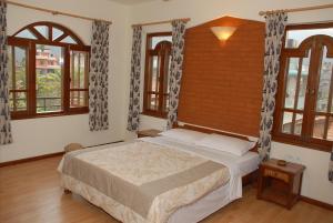 a bedroom with a bed in a room with windows at Vardan Resort n' Apartment in Pokhara