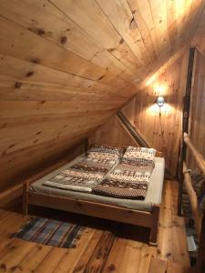 um quarto com uma cama num sótão de madeira em Labanoro pasaka - Elenutės namai em Berniūnai