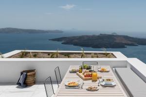 una mesa con platos de comida en el balcón en White Ark en Fira