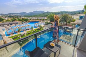 Orka Cove Hotel Penthouse & Suites Adults Only في فتحية: امرأة تقف على شرفة وتطل على حمام سباحة