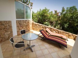 un patio con una mesa de cristal, sillas y una pared de piedra. en Nautilus-Bay Apartments - Apartments 112 - Casa Gorma, en Zavala
