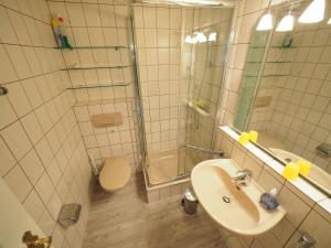uma casa de banho com um chuveiro, um lavatório e um WC. em Appartement-67 em Westerland