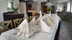einen langen Tisch mit weißen Servietten und Gläsern darauf in der Unterkunft Landgasthof Zur Fichte in Bärenstein